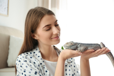 Photo of Woman holding bearded lizard at home. Exotic pet