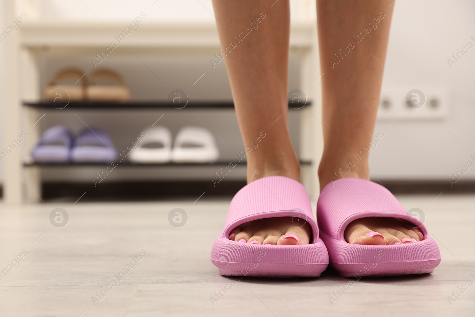 Photo of Woman wearing comfortable rubber slippers indoors, closeup. Space for text