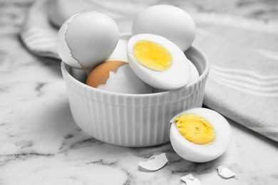 Photo of Bowl with hard boiled eggs on white marble table