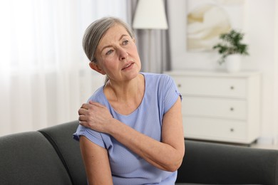 Photo of Arthritis symptoms. Woman suffering from pain in shoulder at home