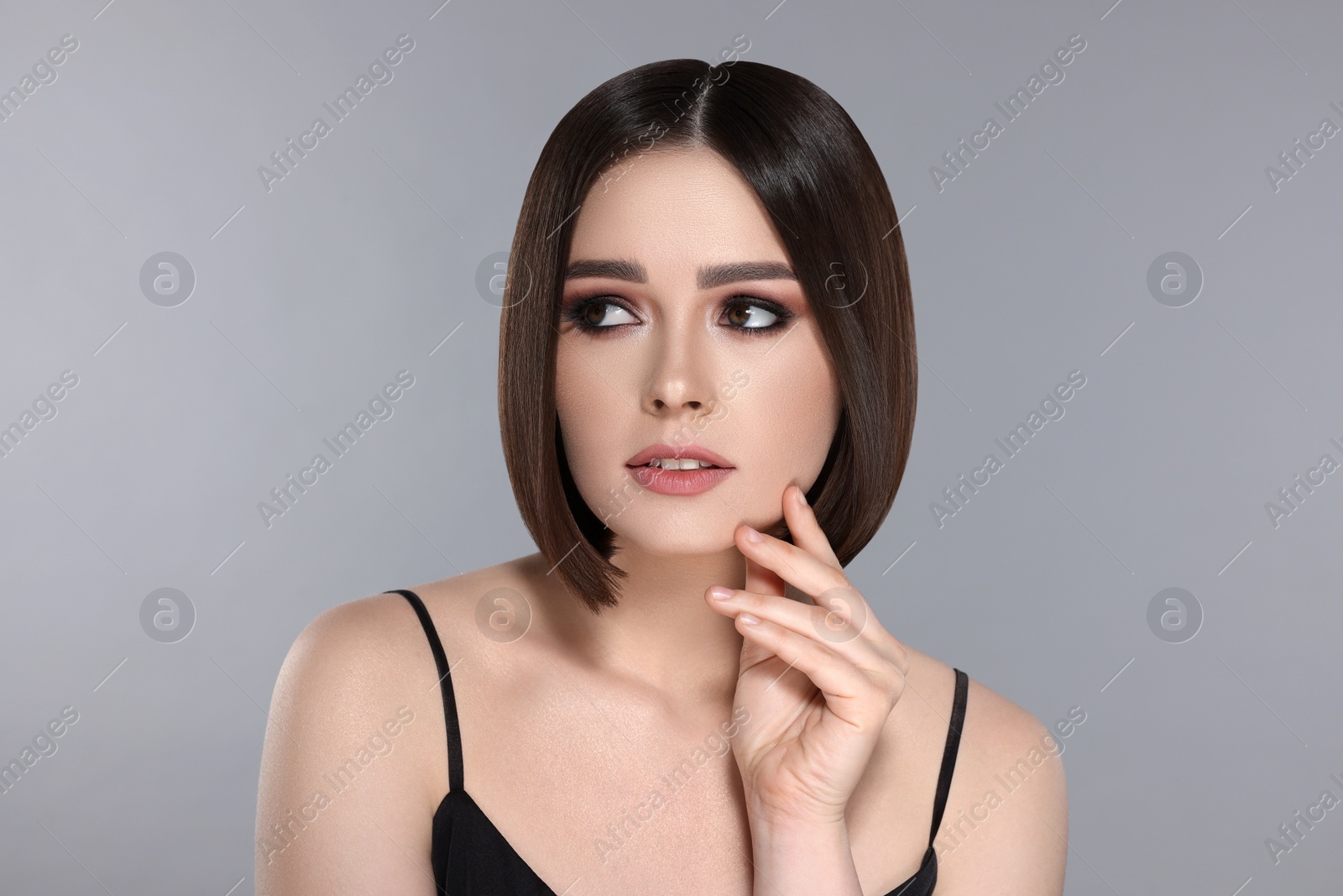 Image of Portrait of pretty young woman with brown hair on grey background