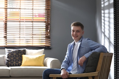 Photo of Teenage boy sitting in armchair at home