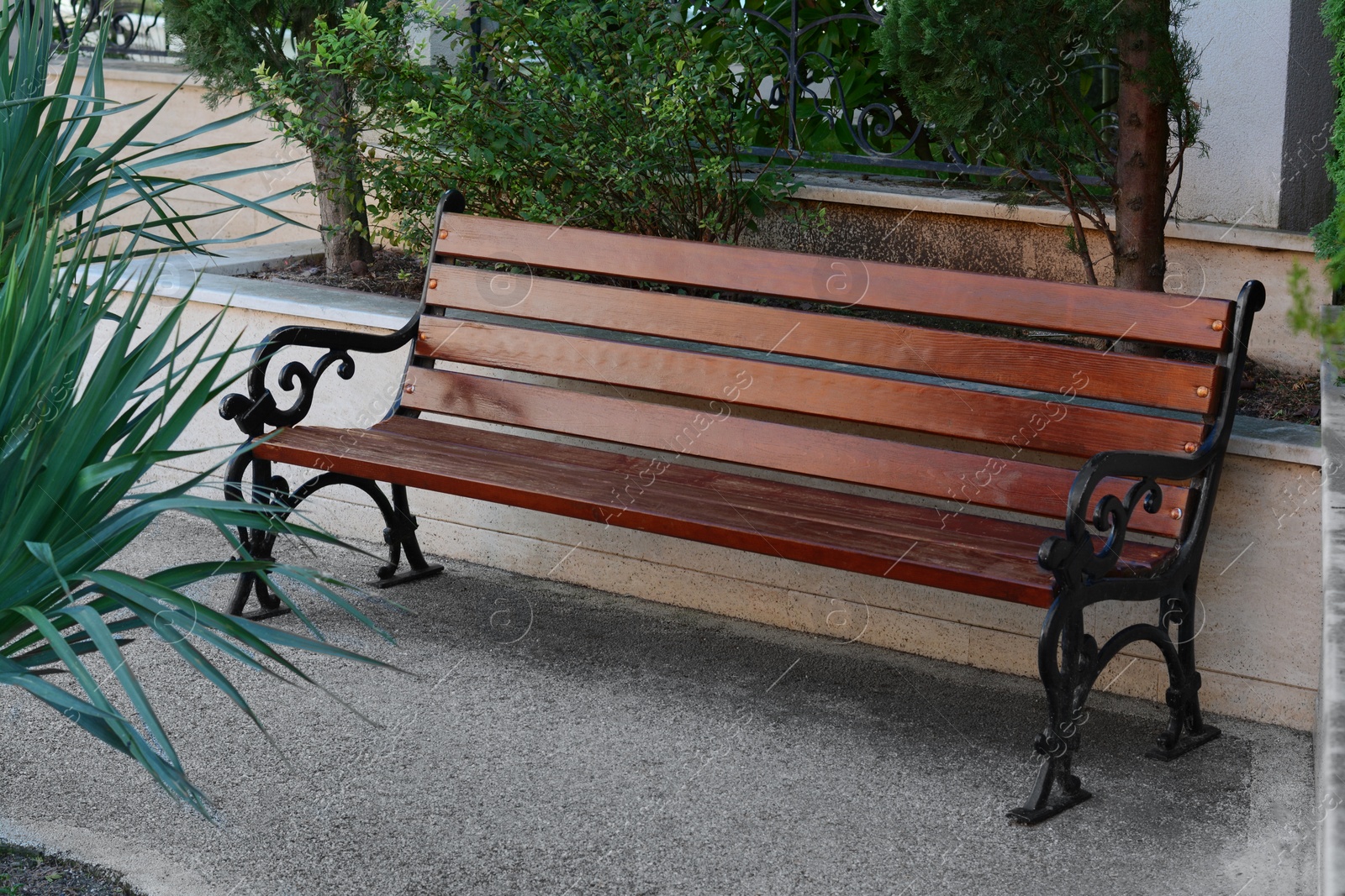 Photo of Beautiful wooden bench with wrought armrests on city street