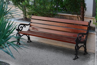 Photo of Beautiful wooden bench with wrought armrests on city street