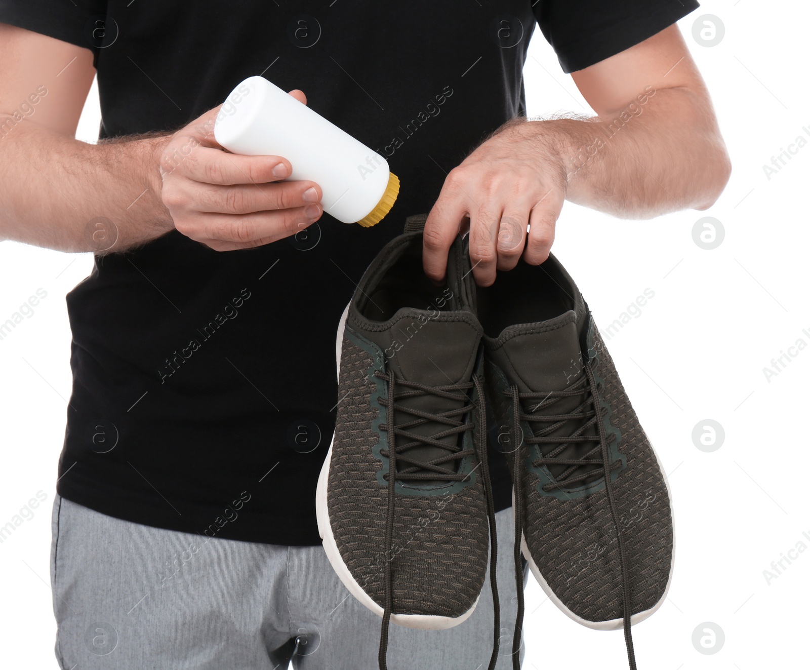 Photo of Young man putting powder freshener into shoes on white background