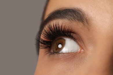 Beautiful young woman with long eyelashes on grey background, closeup