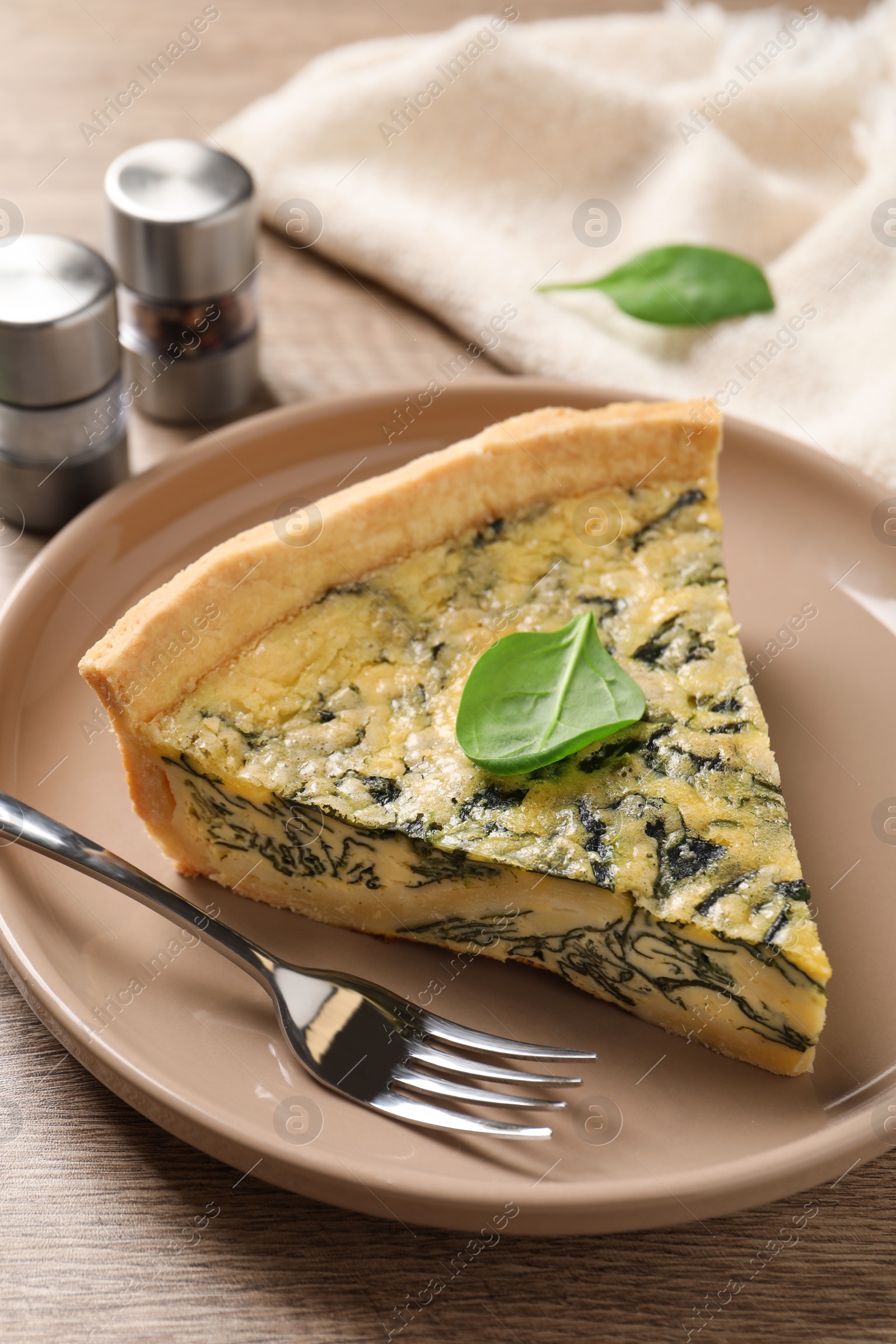 Photo of Piece of delicious homemade spinach pie and fork on wooden table