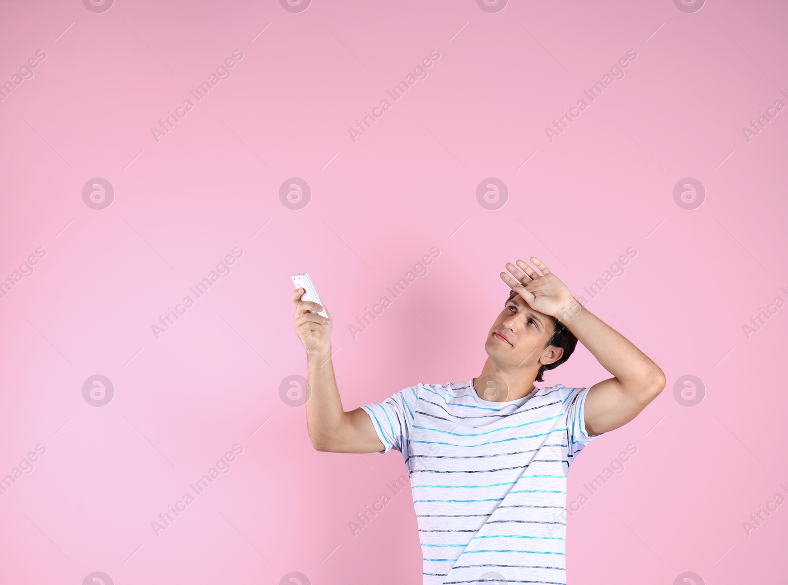 Photo of Young man suffering from heat on color background. Air conditioner malfunction