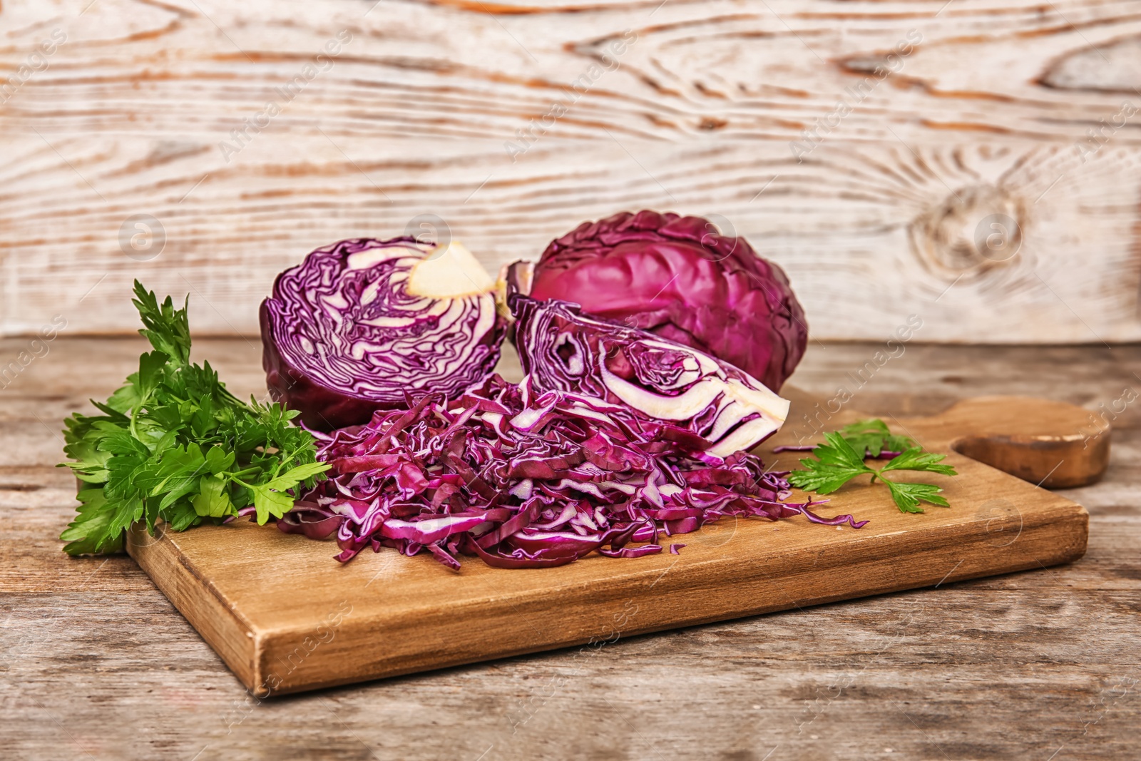 Photo of Wooden board with chopped purple cabbage and parsley on table