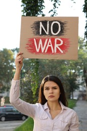 Sad woman holding poster with words No War on city street