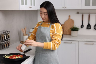 Beautiful woman cooking vegetable dish in kitchen. Space for text