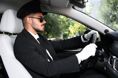 Photo of Young handsome driver in luxury car. Chauffeur service
