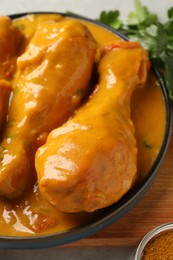 Photo of Tasty chicken curry, spice and parsley on wooden board, closeup