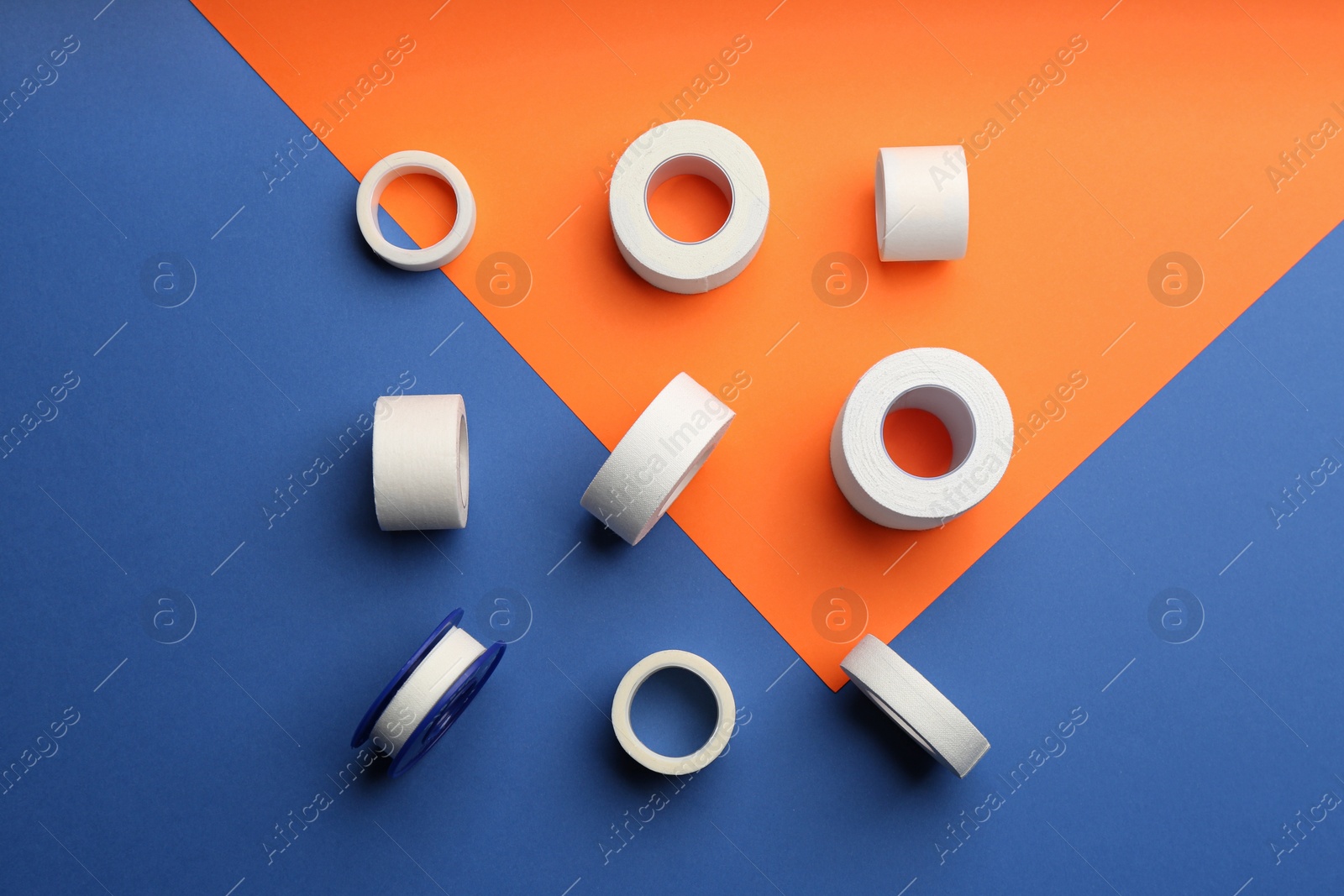 Photo of Sticking plaster rolls on color background, flat lay