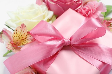 Photo of Gift box and beautiful flowers, closeup view