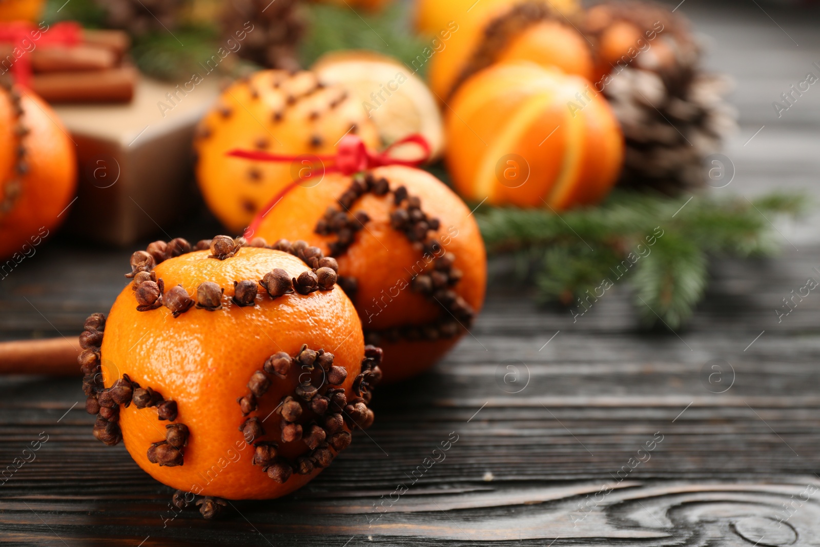 Photo of Pomander balls made of fresh tangerines and cloves on wooden table, space for text