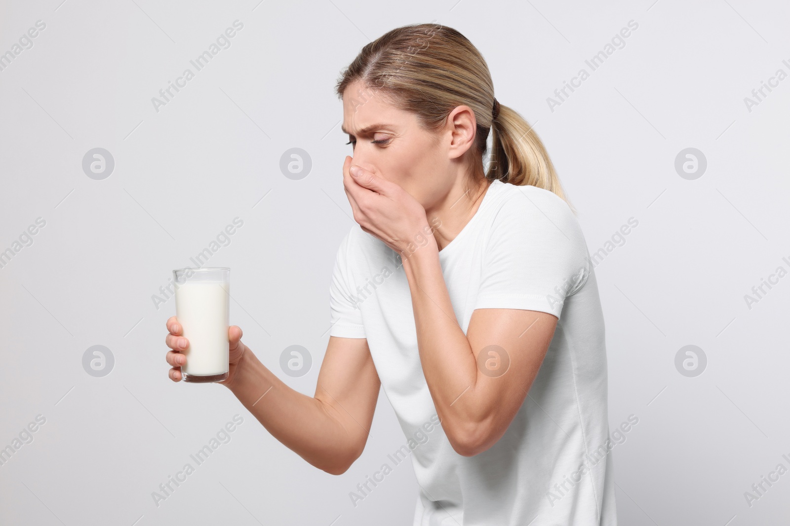 Photo of Woman with glass of milk suffering from lactose intolerance on white background