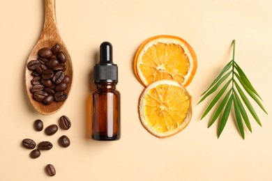 Bottle of organic cosmetic product, coffee beans, dried orange slices and green leaf on beige background, flat lay