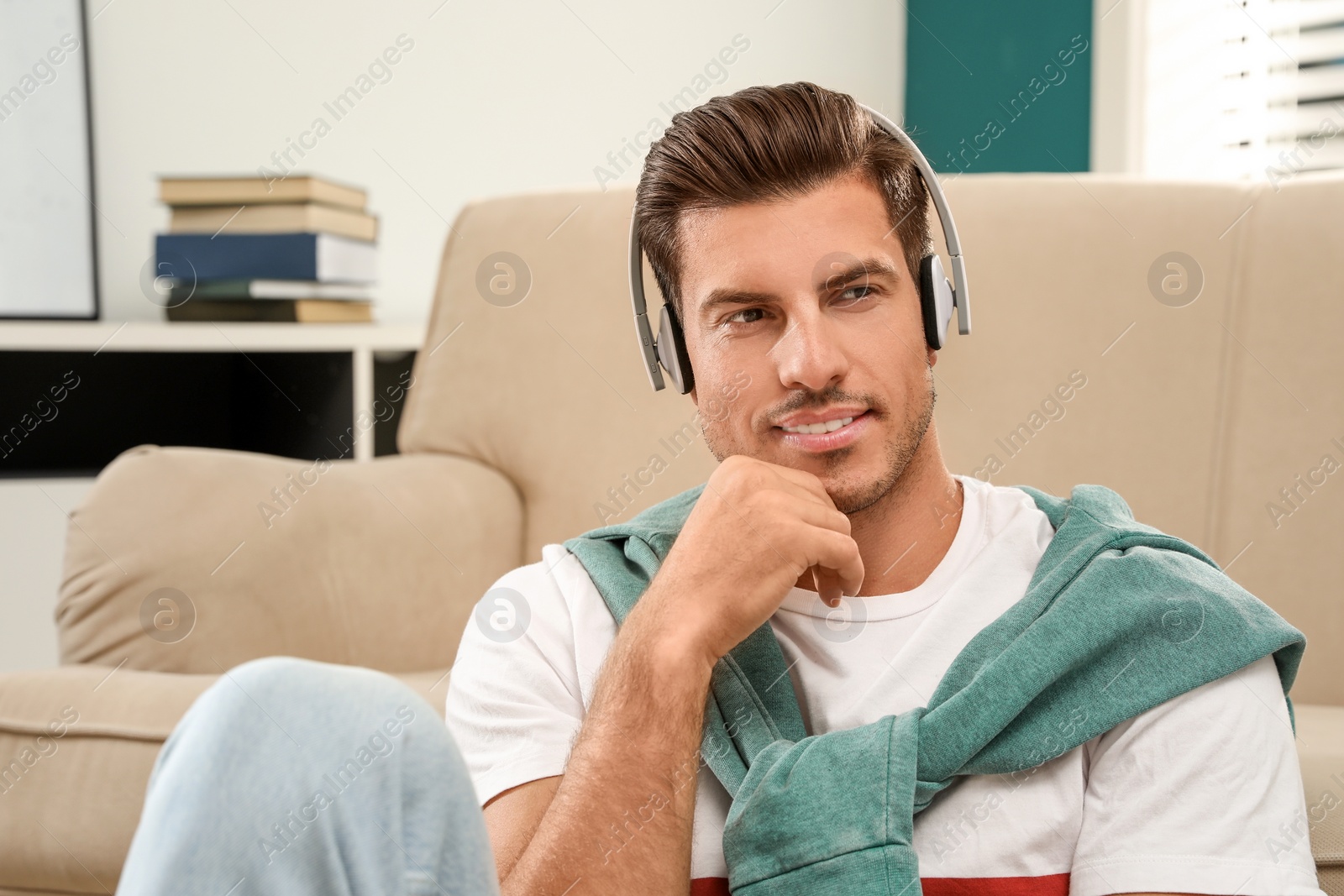 Photo of Man listening to audiobook near sofa at home