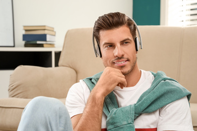 Man listening to audiobook near sofa at home