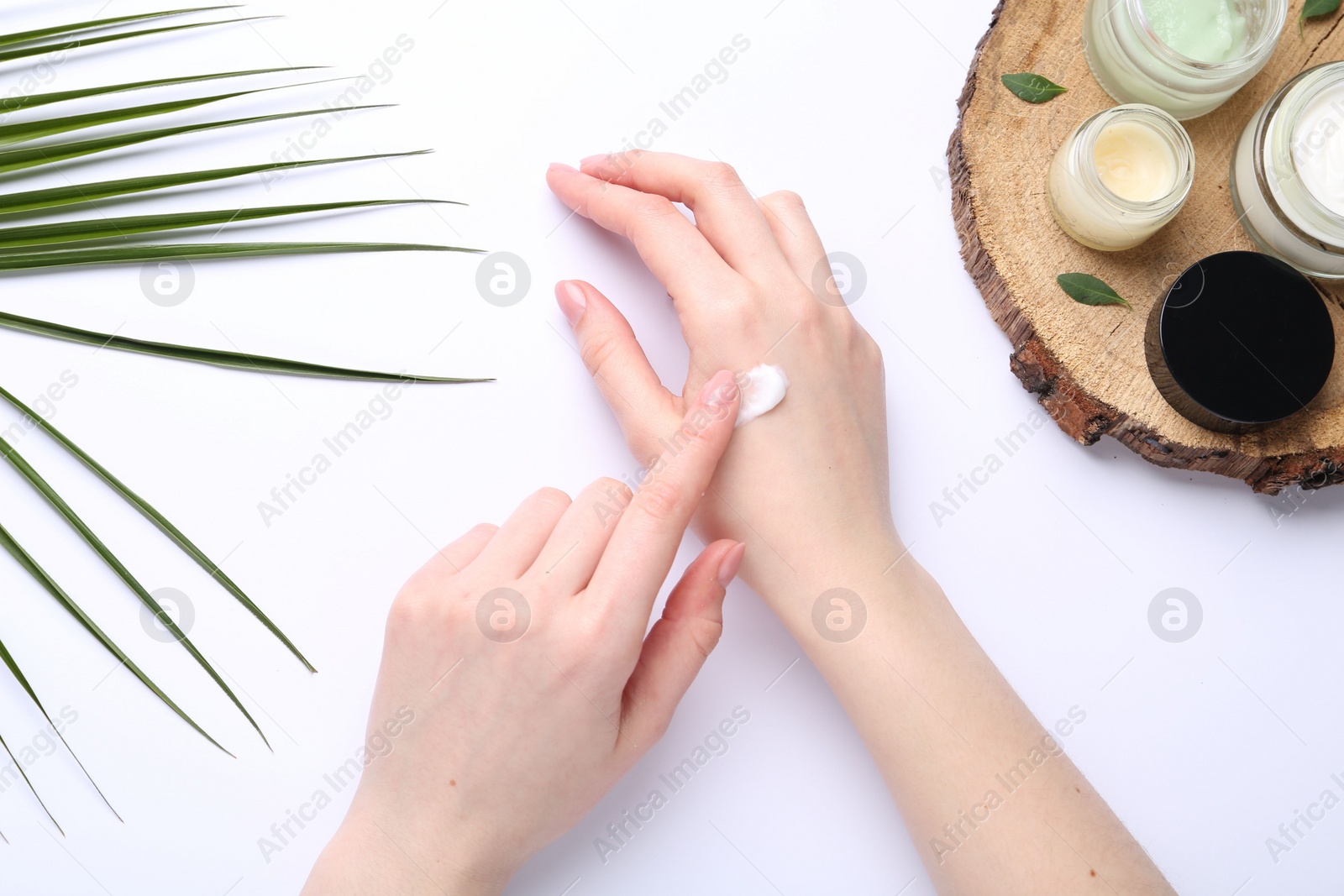 Photo of Woman applying hand cream on white background, top view