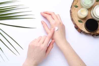 Photo of Woman applying hand cream on white background, top view