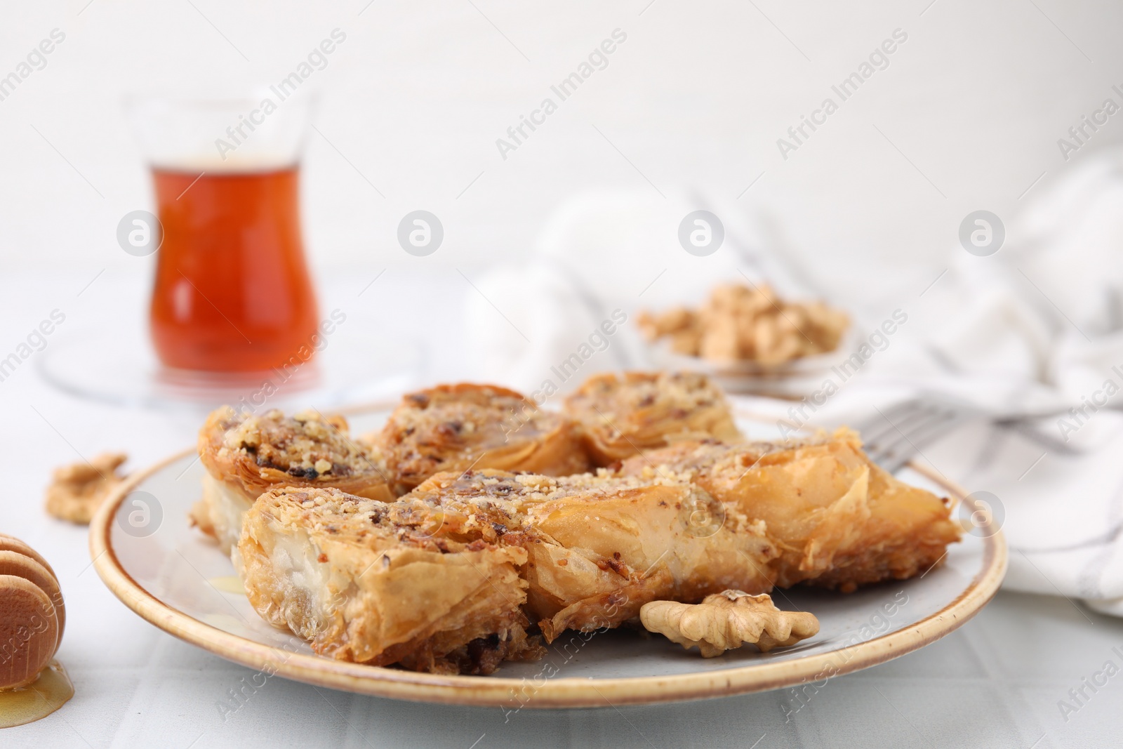 Photo of Eastern sweets. Pieces of tasty baklava on white tiled table, closeup