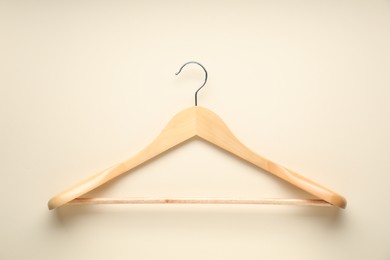 Empty wooden hanger on beige background, top view