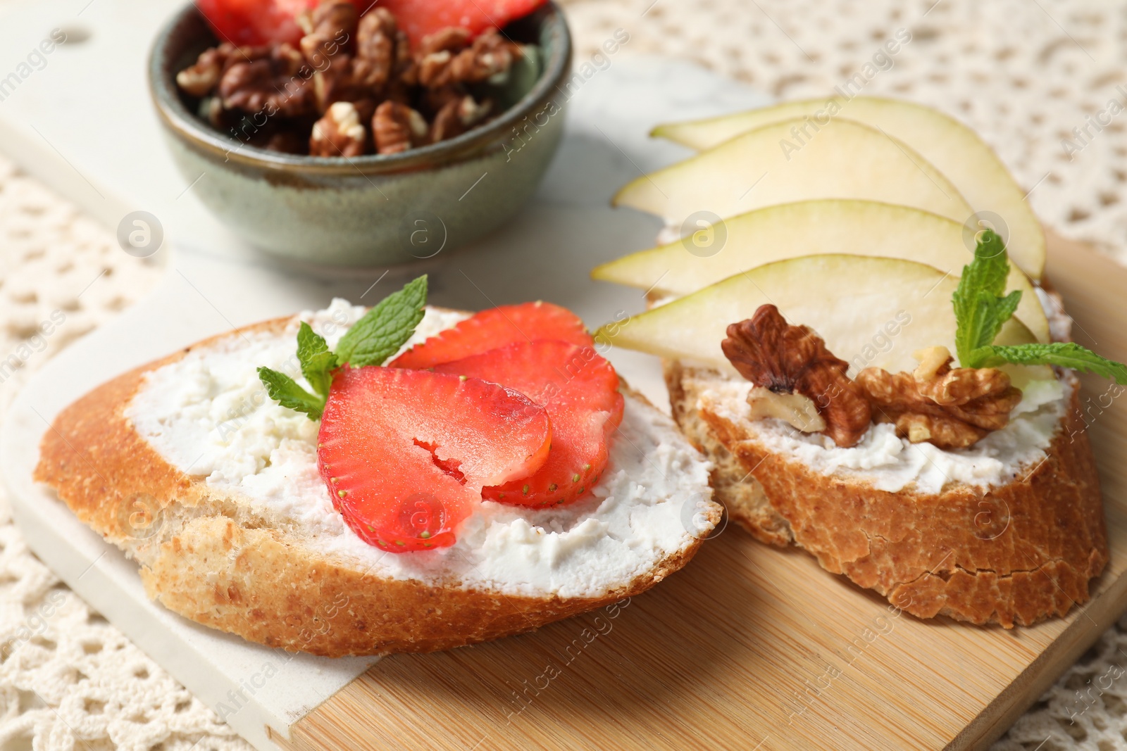 Photo of Delicious bruschettas with fresh ricotta (cream cheese), strawberry, mint and pear on table, closeup