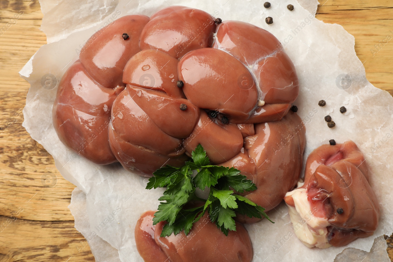 Photo of Fresh raw kidneys with seasonings on wooden table, top view