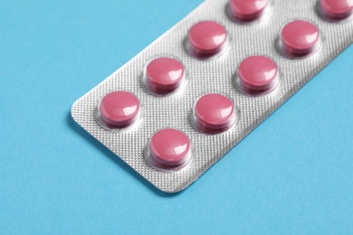 Photo of Pills in blister on blue background, closeup