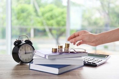 Photo of Woman stacking coins on table. Tax calculation