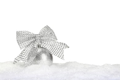 Beautiful silver Christmas ball with bow on snow against white background