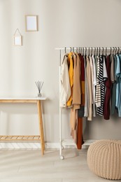 Rack with stylish clothes in cozy room interior. Fast fashion