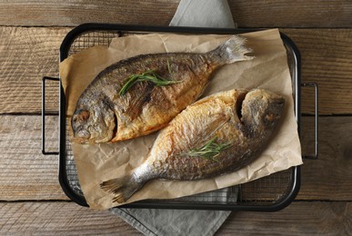 Delicious dorado fish with rosemary on wooden table, top view