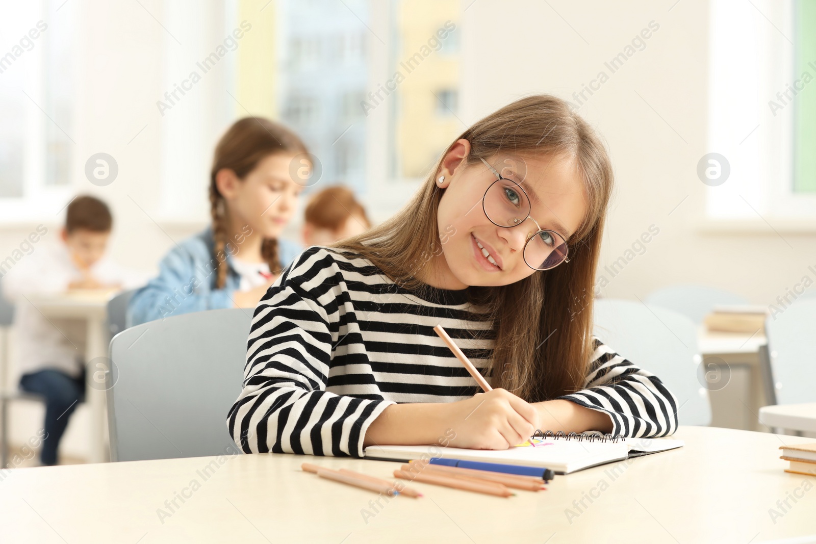 Photo of Portrait of smiling little girl studying in classroom at school