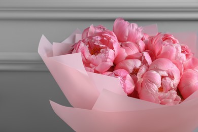 Bouquet of beautiful pink peonies near grey wall, closeup