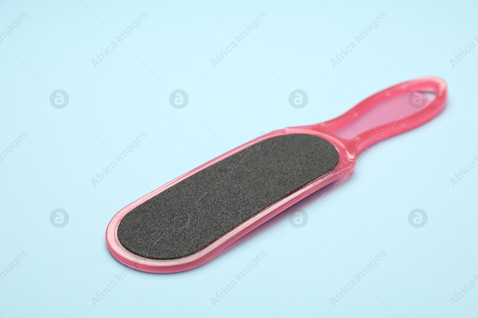 Photo of Pink foot file on light blue background, space for text. Pedicure tool