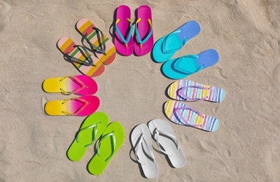 Photo of Flat lay composition with flip flops on sand, space for text. Summer beach accessories