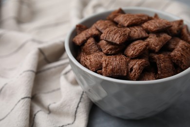 Photo of Chocolate cereal pads in bowl on grey table, closeup. Space for text