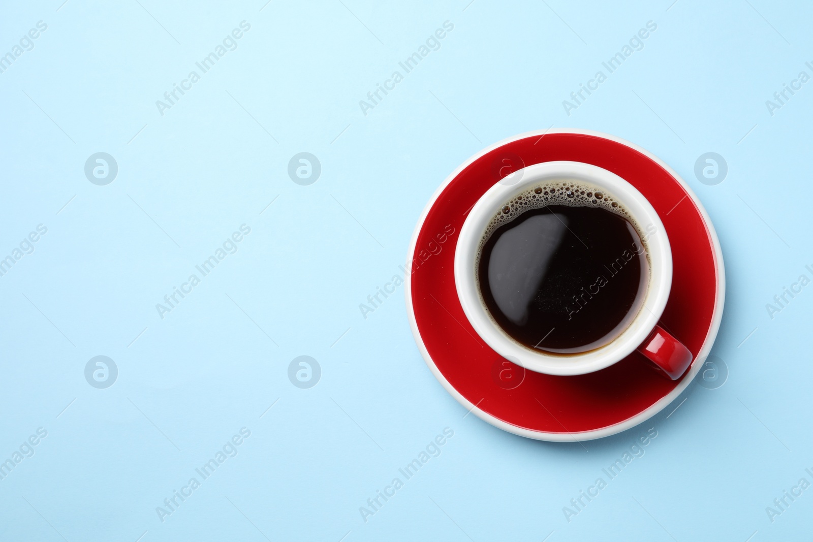 Photo of Aromatic coffee in cup on light blue background, top view. Space for text