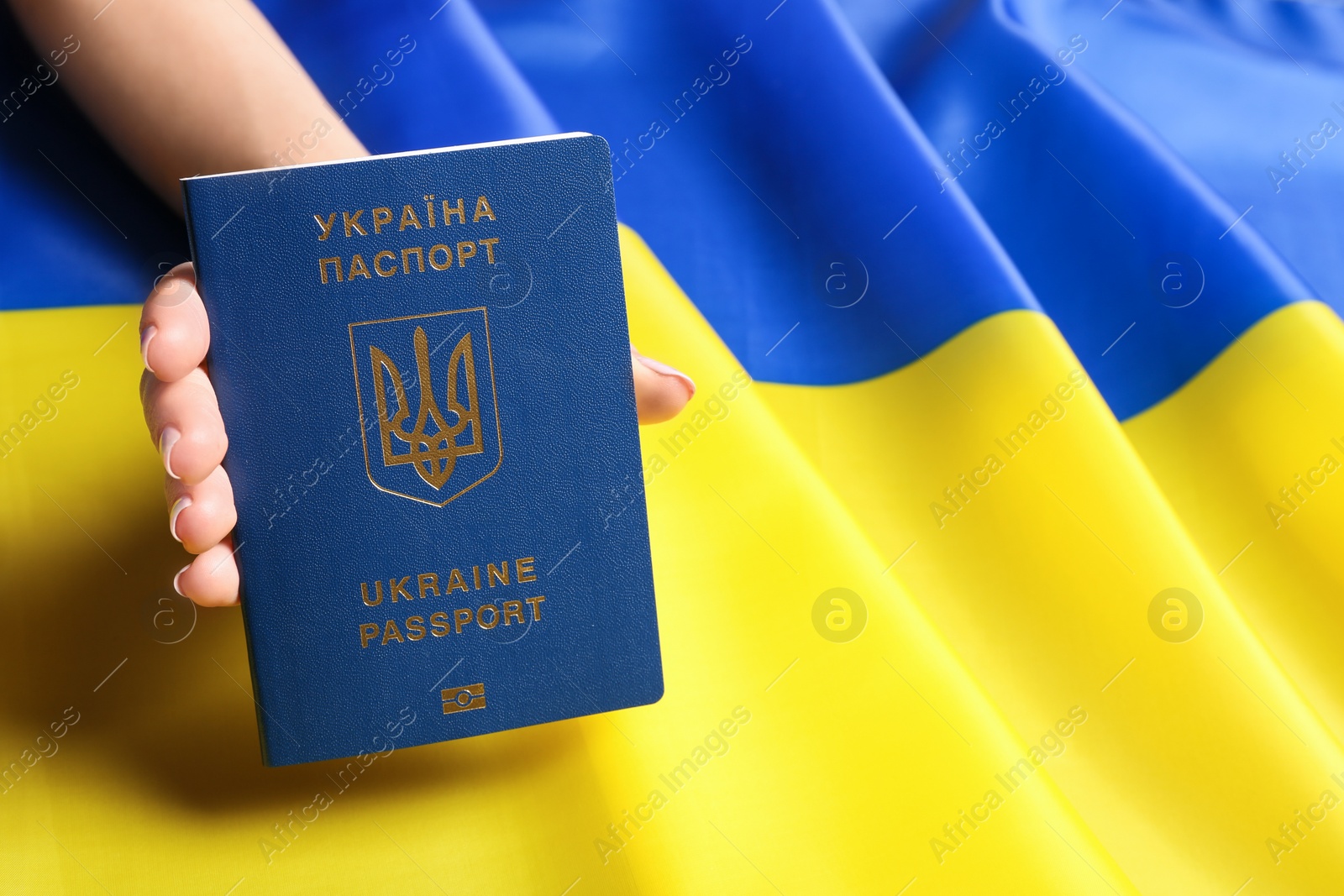 Photo of Woman holding Ukrainian travel passport on national flag, closeup with space for text. International relationships
