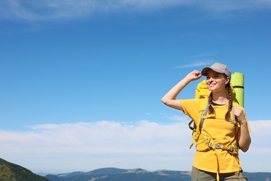 Photo of Young woman with backpack in mountains. Space for text