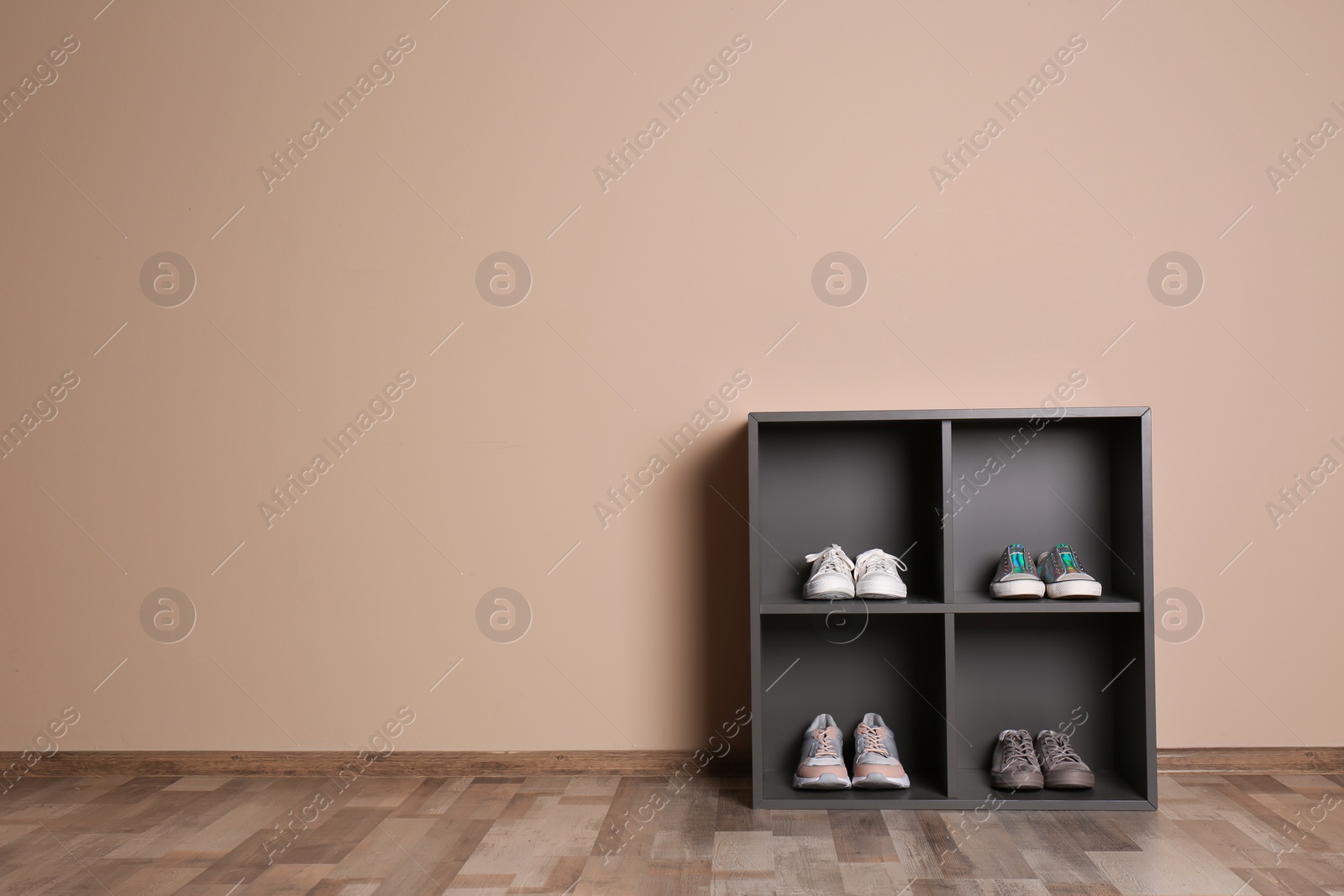 Photo of Modern cabinets with different sneakers near color wall, space for text