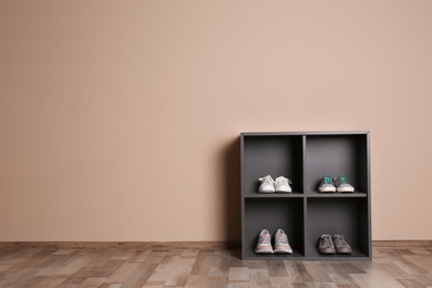 Photo of Modern cabinets with different sneakers near color wall, space for text