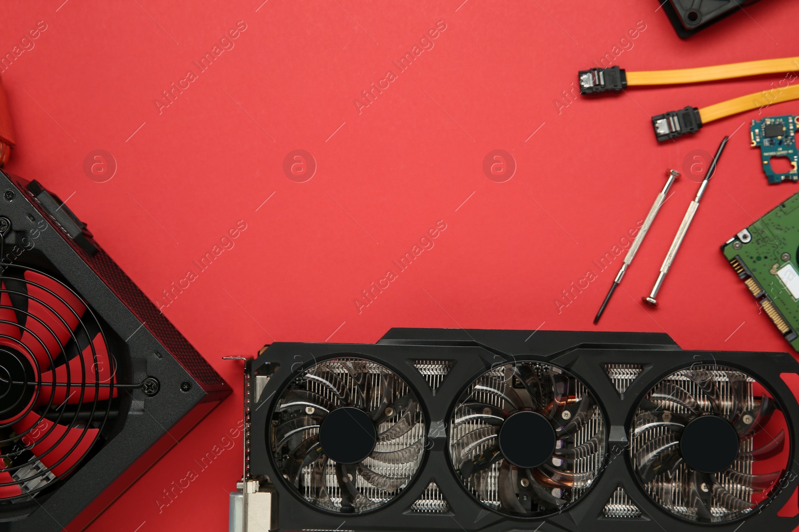 Photo of Graphics card and other computer hardware on red background, flat lay. Space for text