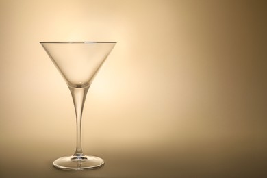 Elegant empty martini glass on beige background. Space for text