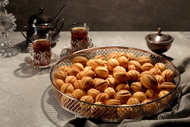 Photo of Delicious walnut shaped cookies and tea on grey table. Tasty pastry carrying nostalgic home atmosphere