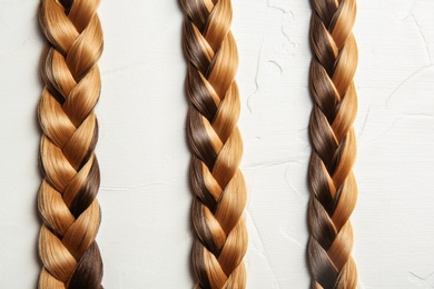 Flat lay composition with braids on light background. Healthy hair