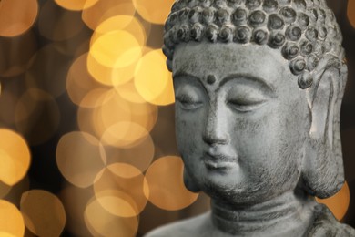 Buddha statue against blurred lights, closeup. Space for text